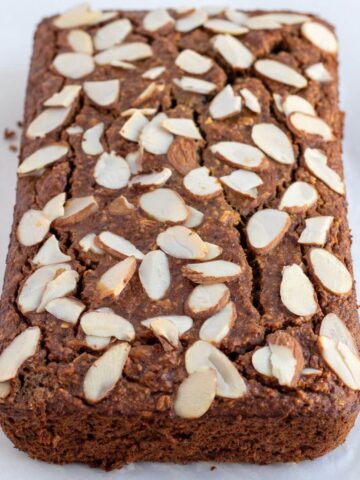 a loaf of flourless banana bread using rolled oats with almond slices toppings
