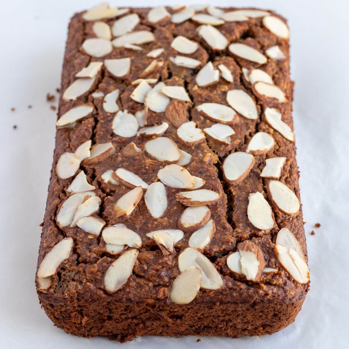 a loaf of flourless banana bread using rolled oats with almond slices toppings