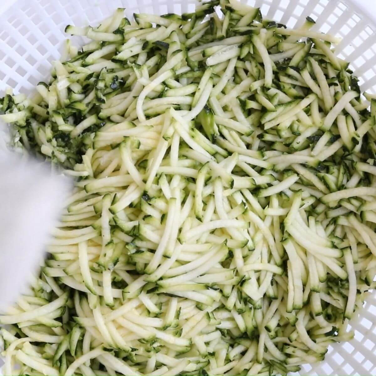 grated zucchini in a strainer. zucchini fritters step 1