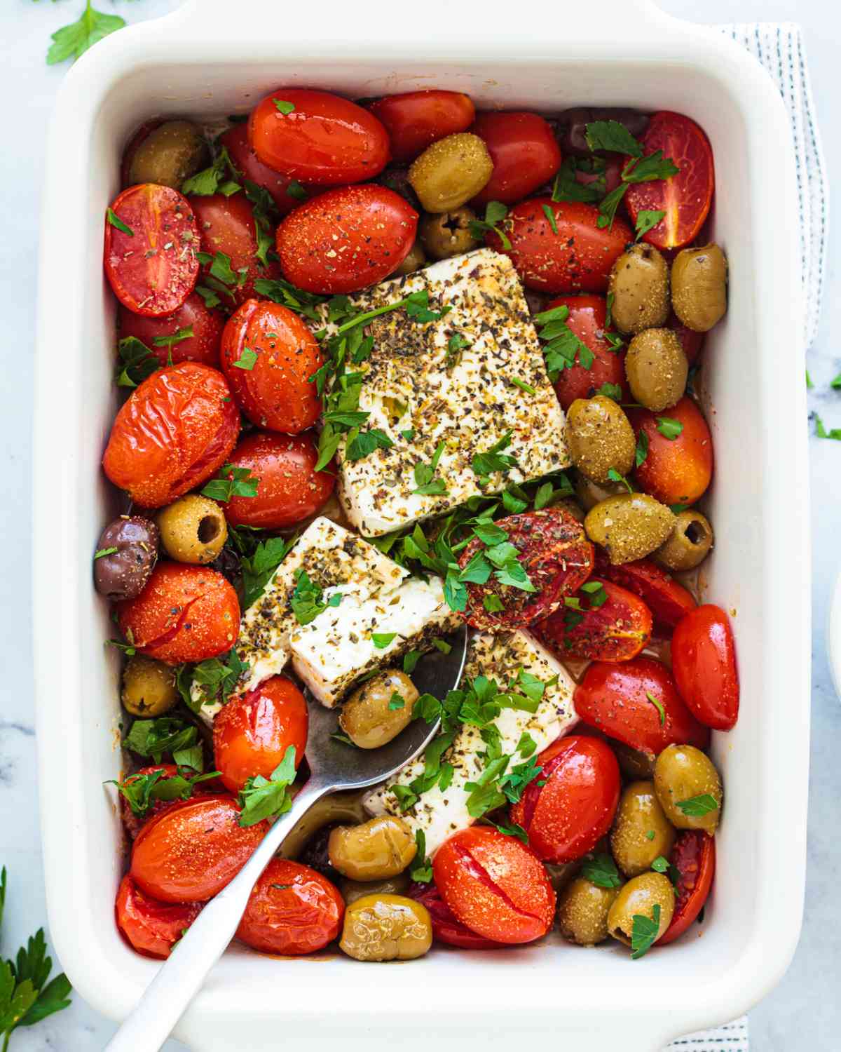 tomatoes and feta in a white baking dish sprinkled with herbs