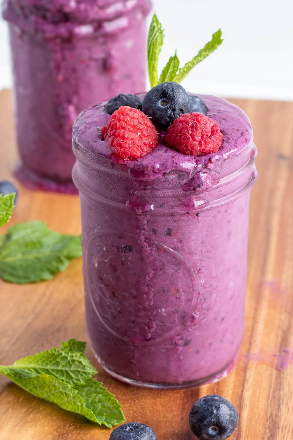 mixed berry smoothie with fresh berries topping on a glass