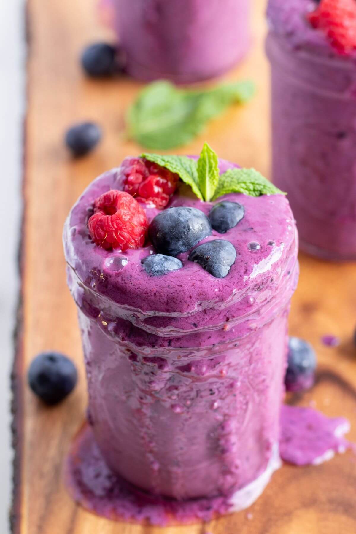 mixed berry smoothie with fresh berries topping on a glass