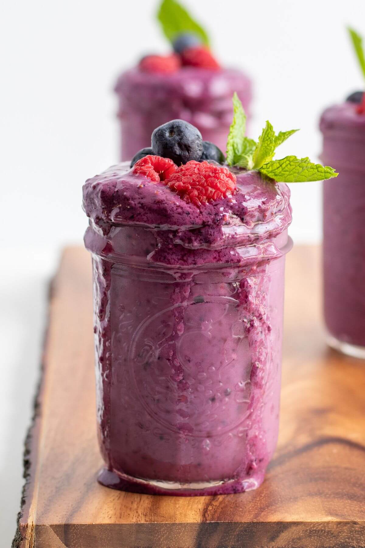 mixed berry smoothie with fresh berries topping on a glass